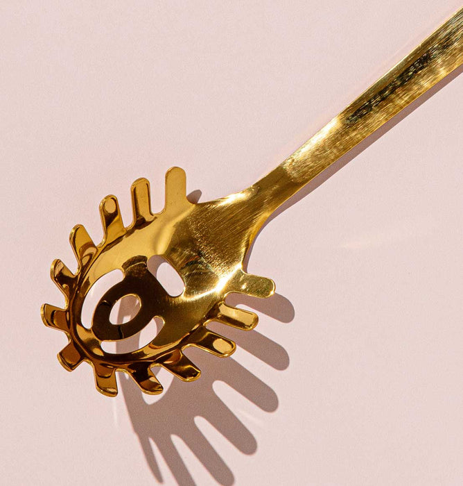 Gold pasta server close-up, serving spoon detail