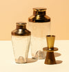 Cocktail shaker in pebbled glass with brass hammered finish. 