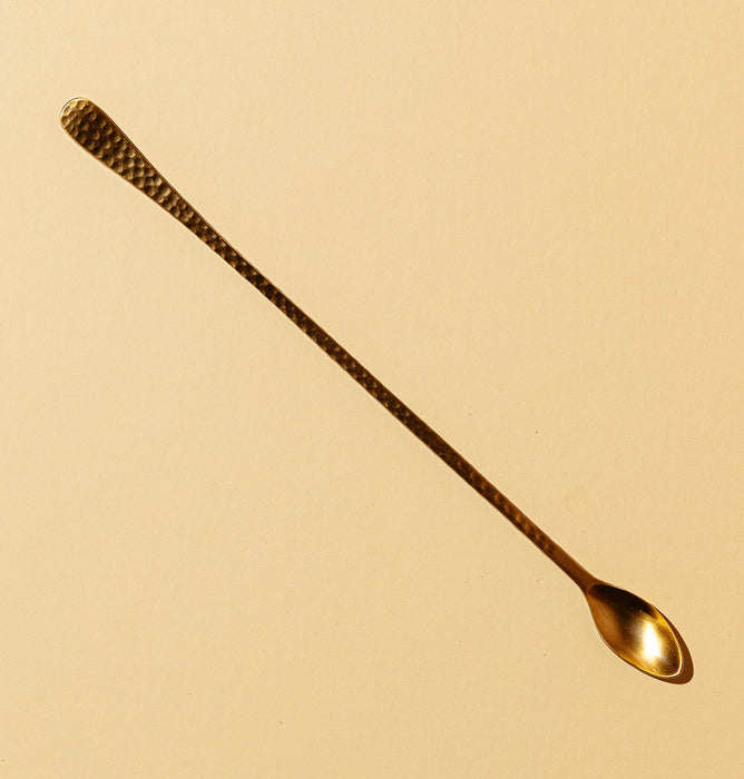 Long spoon in hammered brass for cocktails and drink mixing