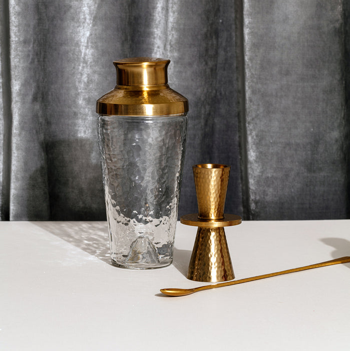 Cocktail shaker, jigger, and long spoon set. Hammered brass copper finish and dimpled glass. 